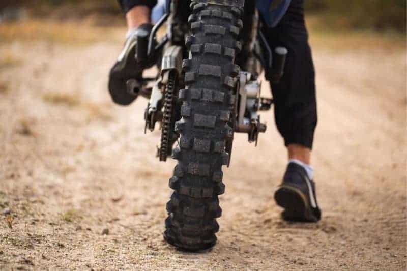 A motorcycle ride wearing trainers.