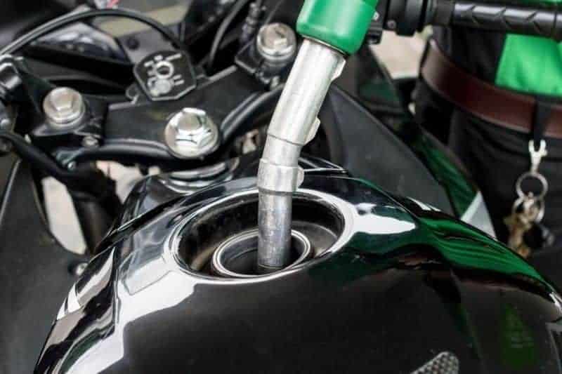 A motorcycle's fuel tank being filled up with gas.