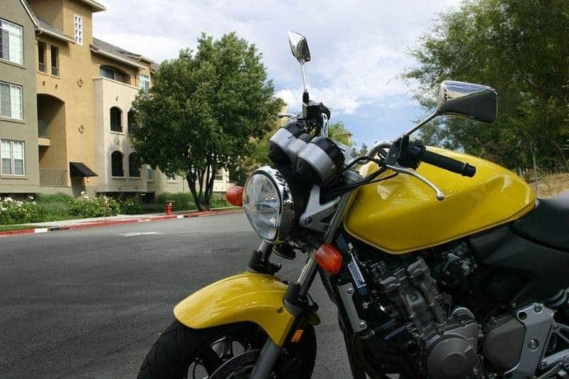 A motorcycle that is kept in a parking lot of an apartment complex.