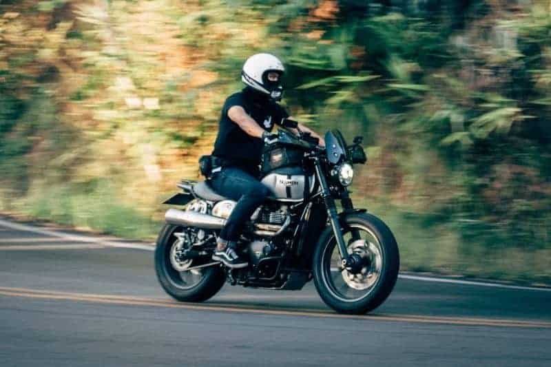 A motorcyclists wearing a white motorcycle helmet.