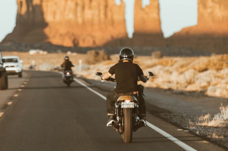 Two motorcyclists riding behind one another.