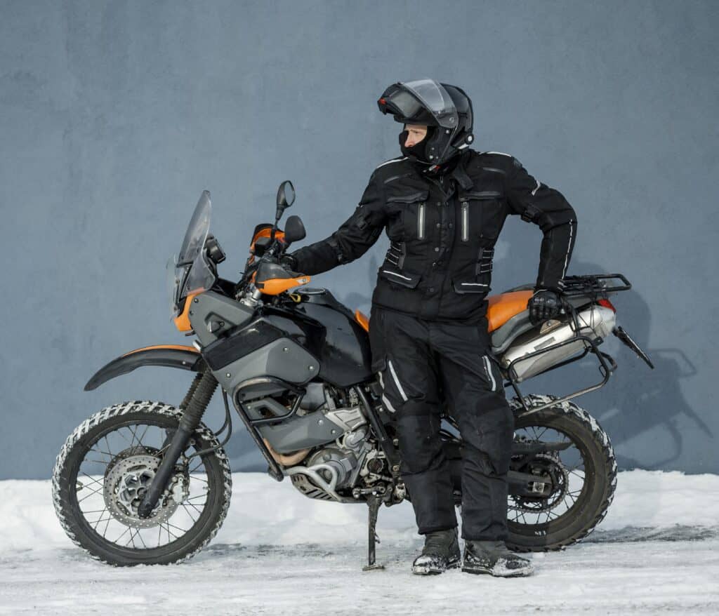 Windchill on Wheels: Decoding Motorcycle Riding Temps Man standing near a wall with his motorcycle in snow